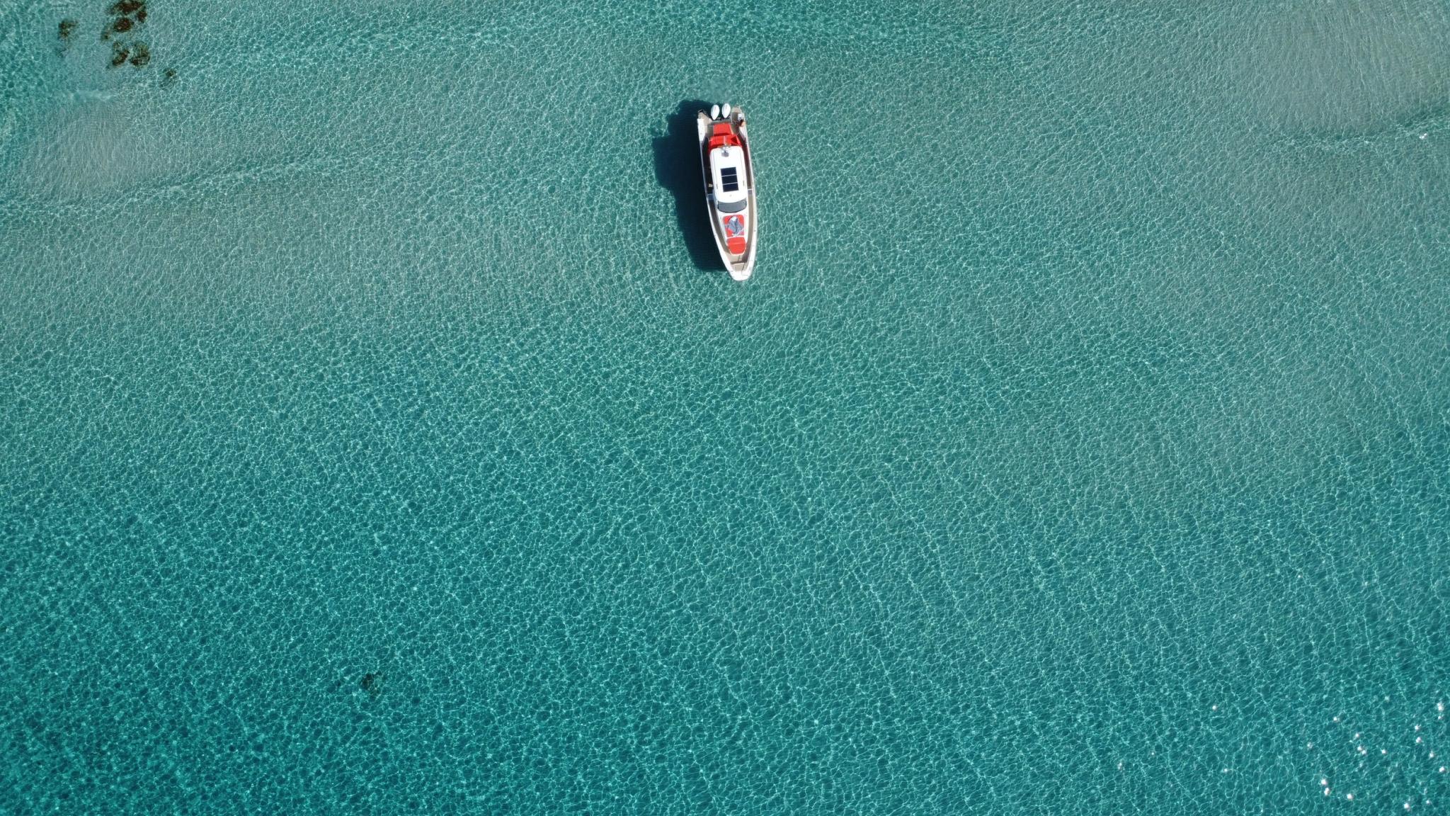 Bateau rouge et blanc ancré dans les eaux turquoise près d'Île-Rousse