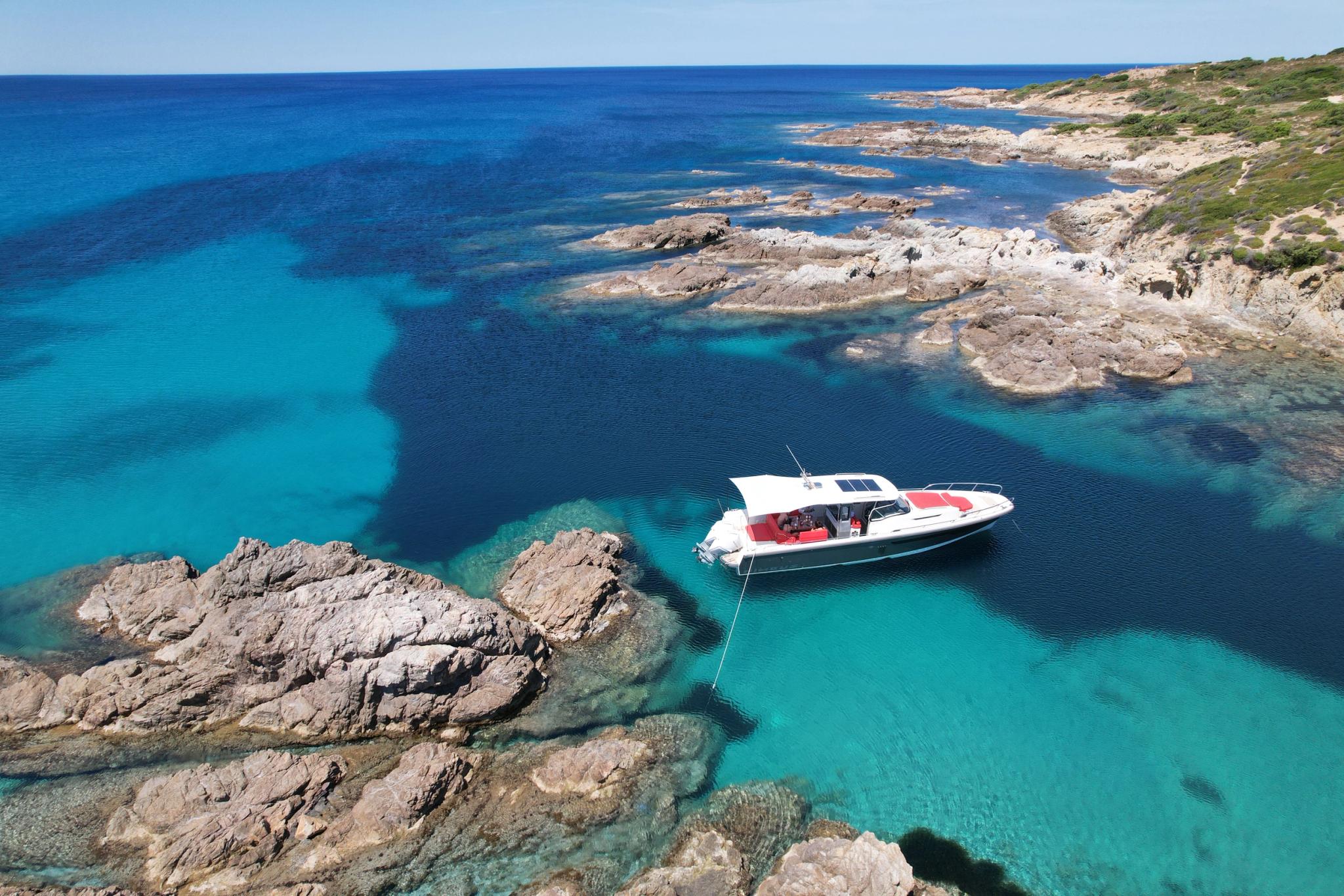 Bateau de plaisance à vendre à Île-Rousse avec vue sur eaux turquoises et côte rocheuse