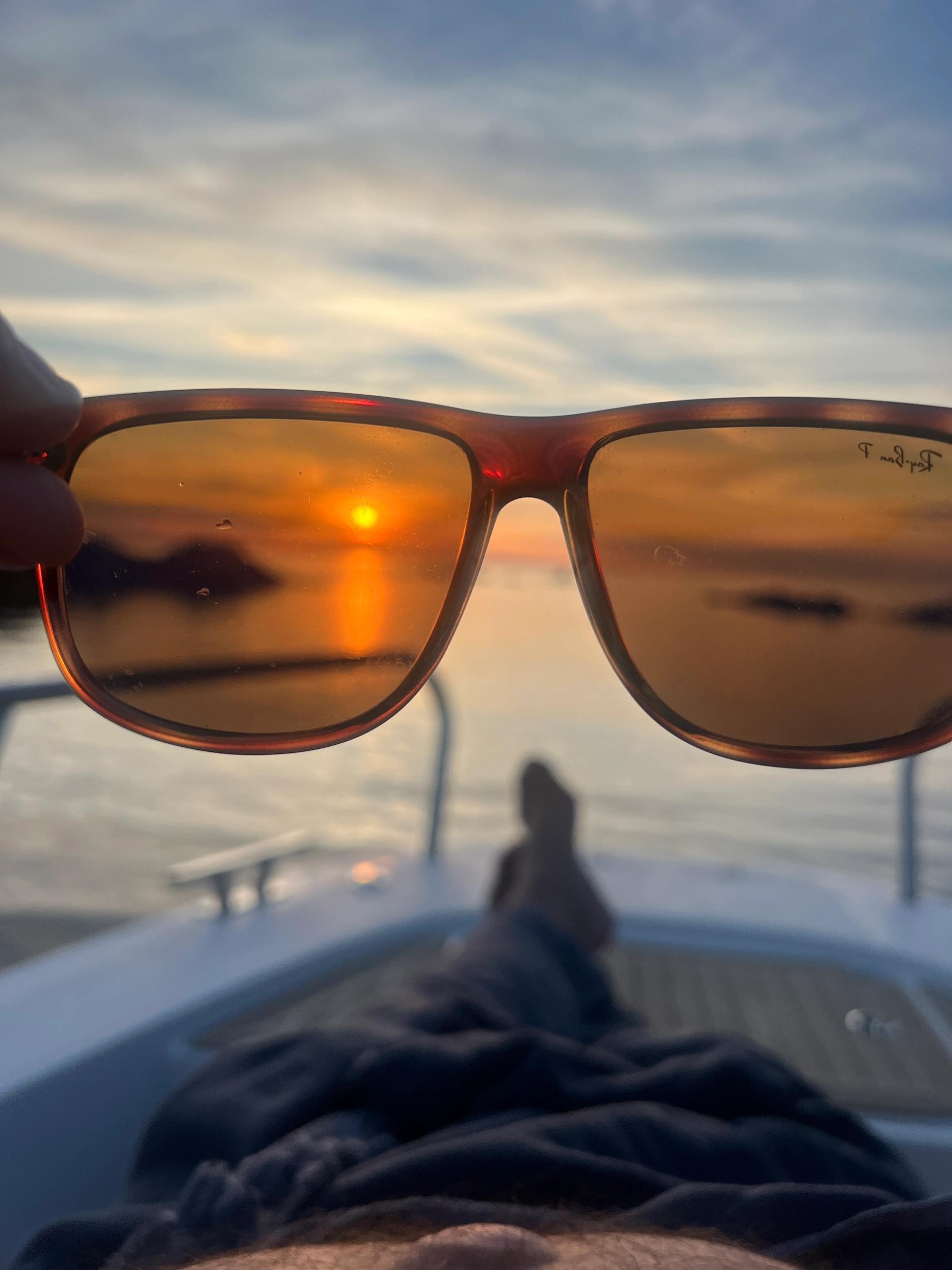 Lunettes de soleil avec vue sur coucher de soleil lors d'une location de bateau à Île-Rousse en Balagne